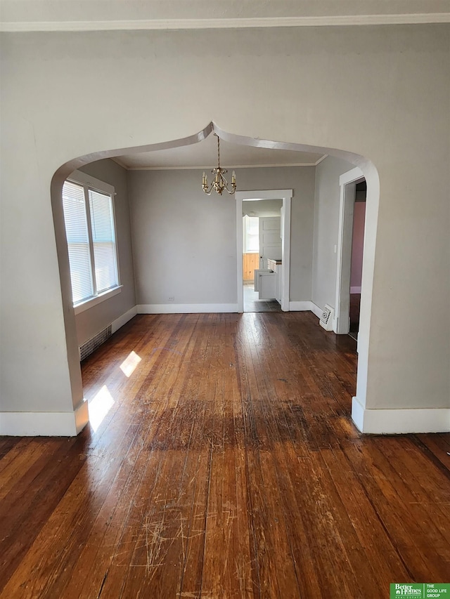 unfurnished room with arched walkways, ornamental molding, wood-type flooring, and visible vents