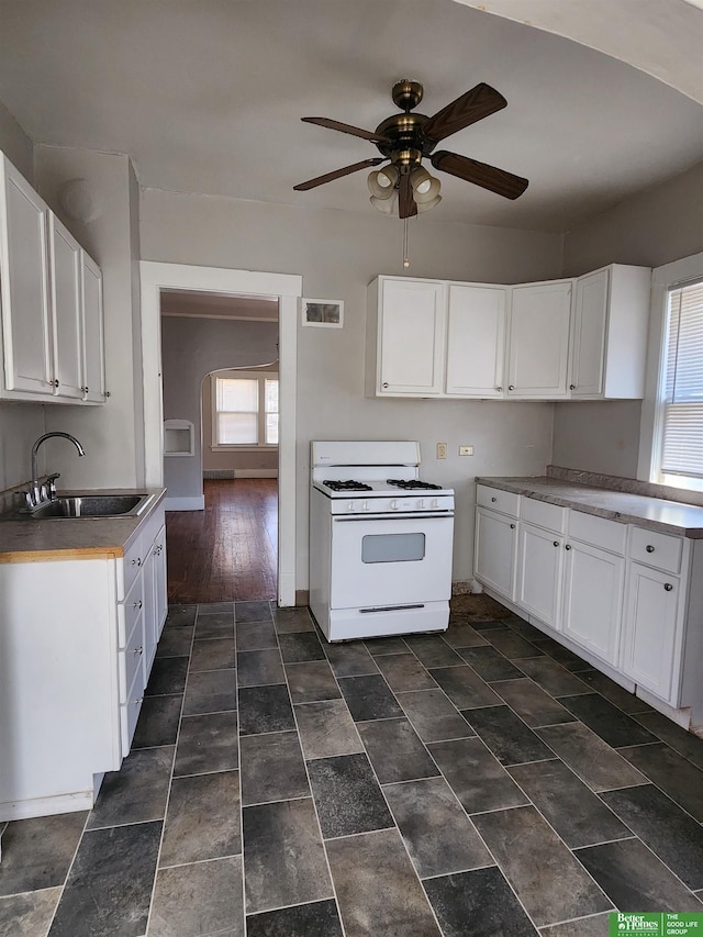 kitchen with white range with gas stovetop, visible vents, ceiling fan, white cabinetry, and a sink