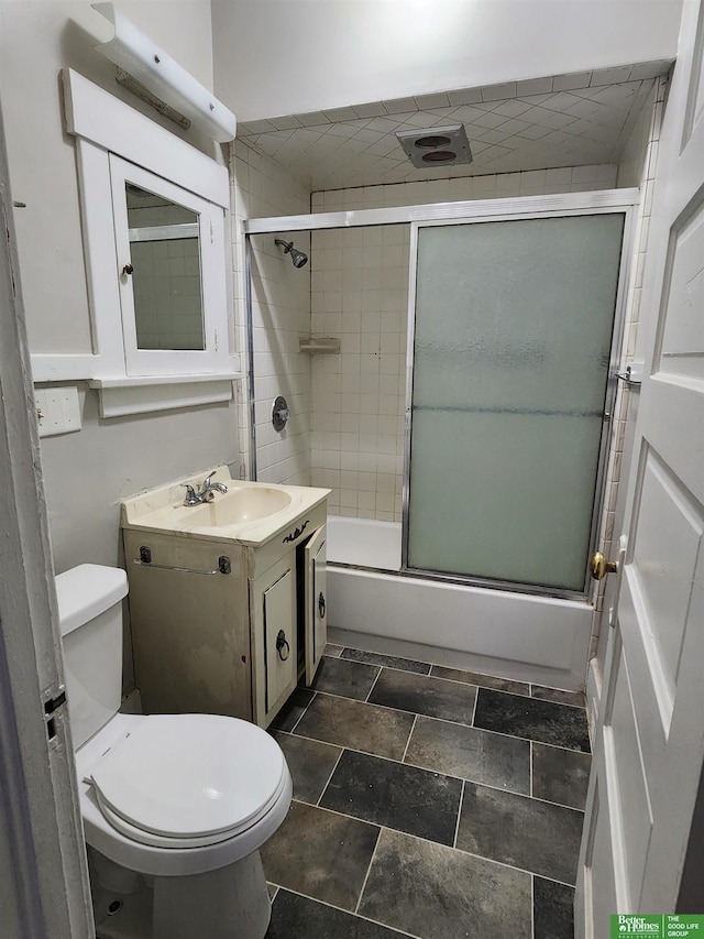 bathroom with combined bath / shower with glass door, vanity, and toilet