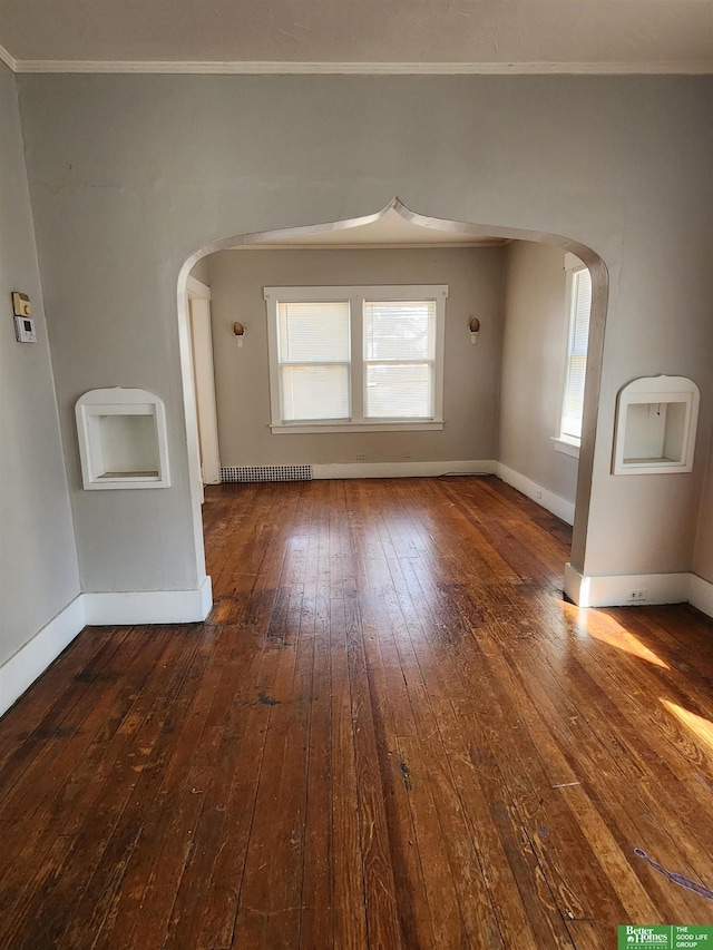 interior space with arched walkways, crown molding, wood-type flooring, and baseboards