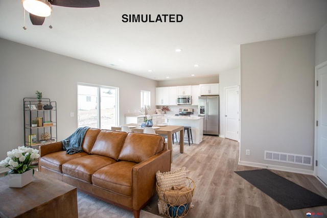 living room featuring ceiling fan, light wood-style flooring, recessed lighting, visible vents, and baseboards