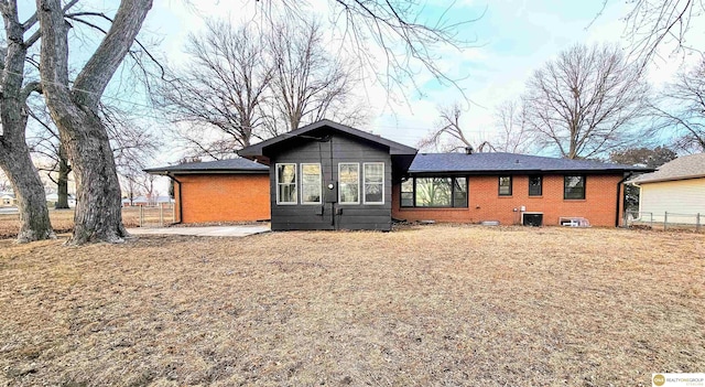 rear view of property with brick siding and fence