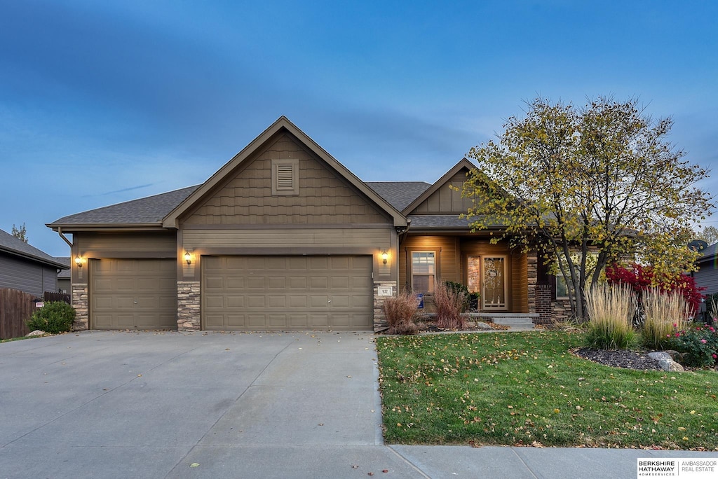 craftsman house featuring an attached garage, driveway, roof with shingles, a front lawn, and board and batten siding