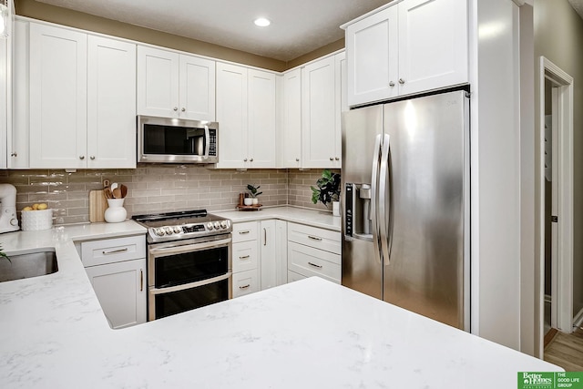 kitchen featuring stainless steel appliances, white cabinets, and backsplash