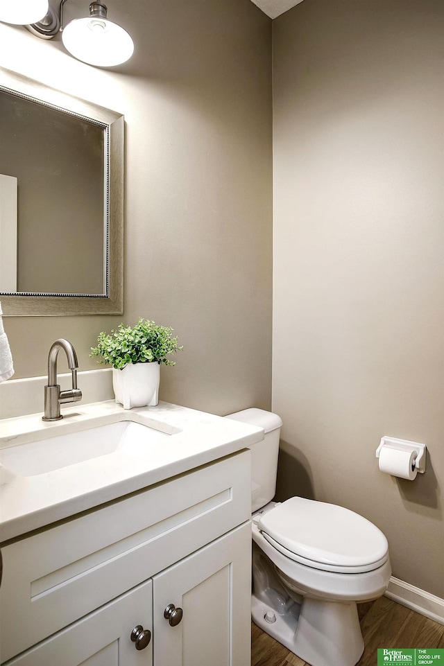 half bath featuring vanity, toilet, and wood finished floors