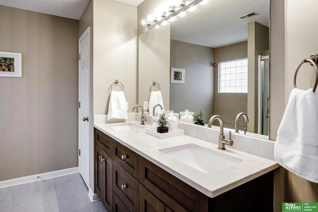 full bathroom featuring double vanity, baseboards, visible vents, and a sink