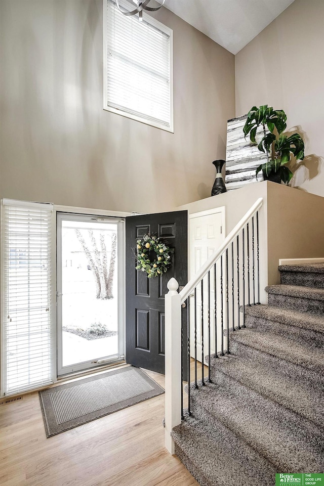 entrance foyer featuring stairway, wood finished floors, visible vents, and a healthy amount of sunlight