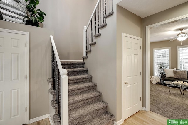 stairs with ceiling fan, baseboards, and wood finished floors