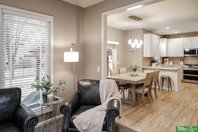 dining space with light wood-type flooring, an inviting chandelier, baseboards, and recessed lighting