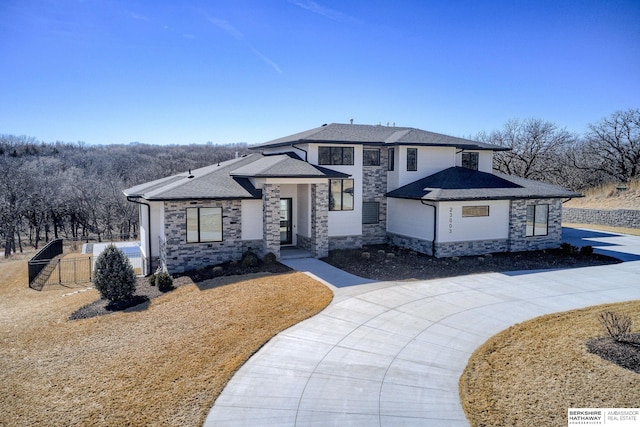 view of front of house featuring a shingled roof and stone siding