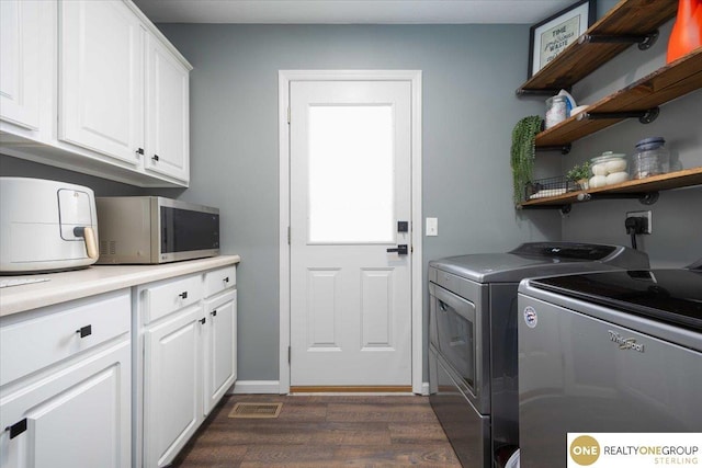 laundry area with visible vents, baseboards, dark wood finished floors, washing machine and dryer, and cabinet space