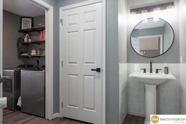 bathroom with washer and dryer, a wainscoted wall, tile walls, and wood finished floors