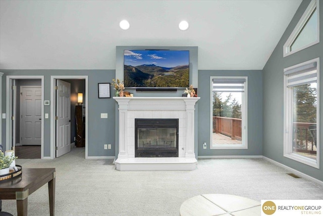 living area featuring visible vents, baseboards, a tiled fireplace, vaulted ceiling, and carpet flooring