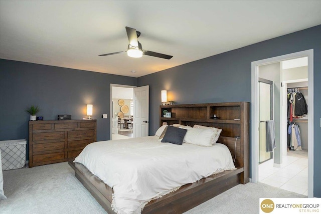 bedroom featuring light carpet, light tile patterned floors, a walk in closet, and a ceiling fan