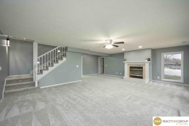 unfurnished living room featuring stairway, baseboards, carpet, and a glass covered fireplace