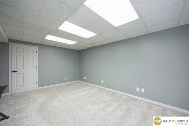 carpeted spare room featuring a paneled ceiling and baseboards