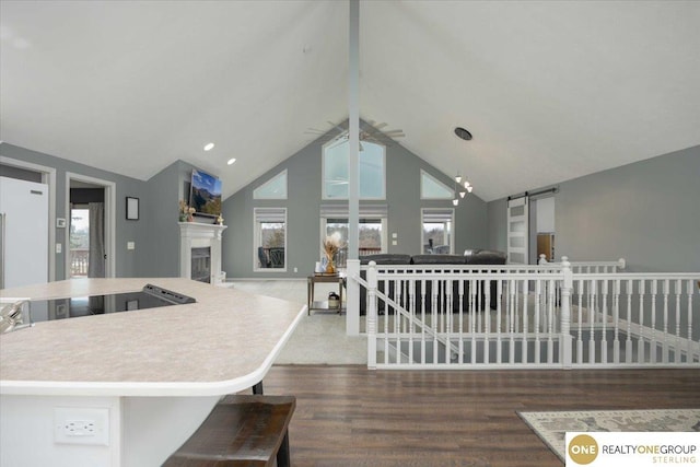 kitchen featuring high vaulted ceiling, a fireplace, a barn door, open floor plan, and a center island