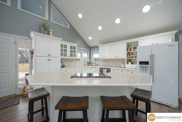 kitchen with open shelves, light countertops, white fridge with ice dispenser, white cabinets, and a sink