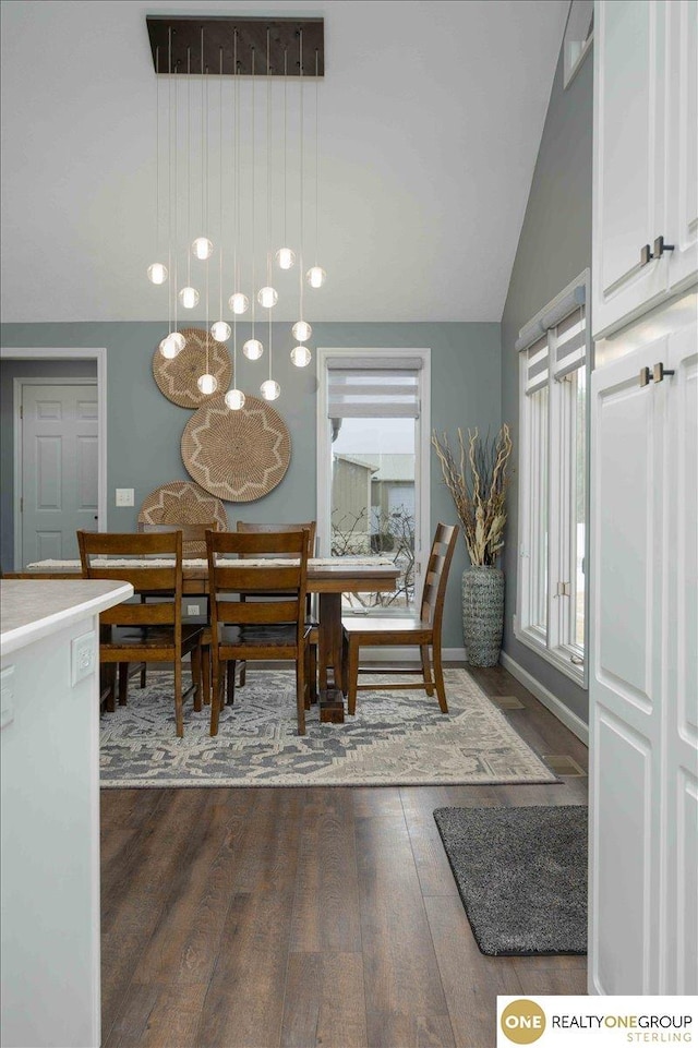 dining room featuring lofted ceiling, dark wood-style floors, and baseboards