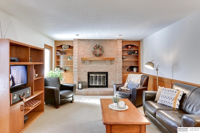 living area featuring carpet floors, built in features, a textured ceiling, and wainscoting