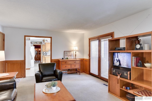 living room with wainscoting, light carpet, visible vents, and a textured ceiling