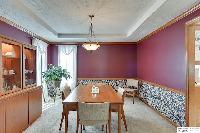 dining area with light carpet, a tray ceiling, and wainscoting