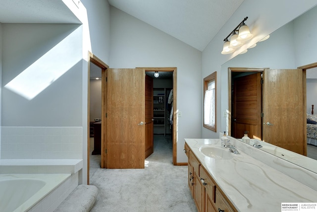 bathroom featuring lofted ceiling, a spacious closet, a garden tub, and vanity