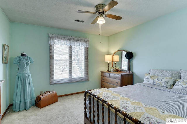 carpeted bedroom with a ceiling fan, visible vents, a textured ceiling, and baseboards