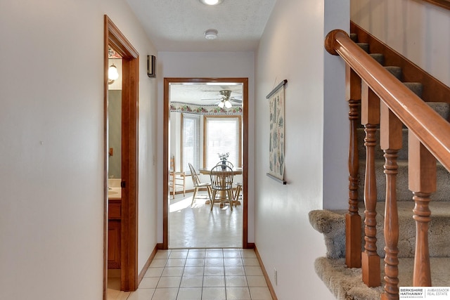 interior space with light tile patterned floors, stairs, baseboards, and a textured ceiling