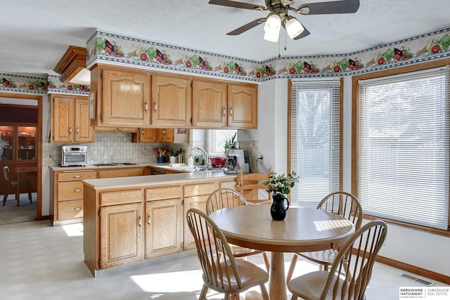 kitchen with a textured ceiling, a peninsula, visible vents, light floors, and stainless steel gas stovetop