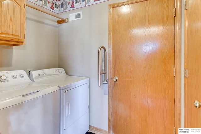 washroom with visible vents, independent washer and dryer, and cabinet space