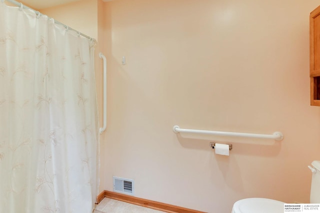 bathroom featuring toilet, a shower with shower curtain, visible vents, and baseboards