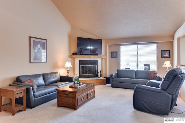 living area featuring vaulted ceiling, a textured ceiling, a tiled fireplace, and light colored carpet