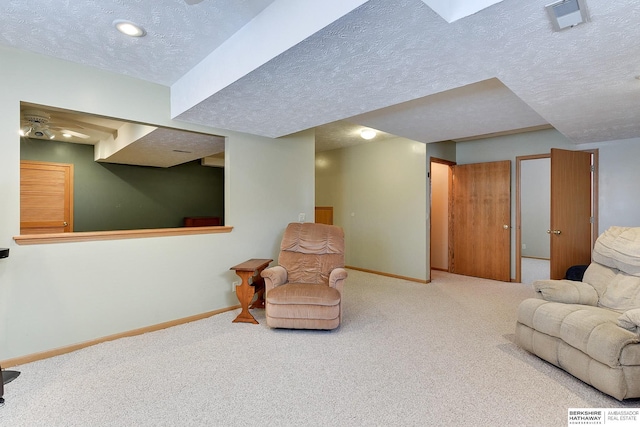 sitting room with carpet floors, a textured ceiling, and baseboards