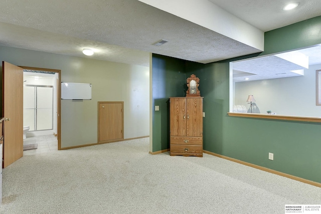 carpeted spare room featuring visible vents, a textured ceiling, and baseboards