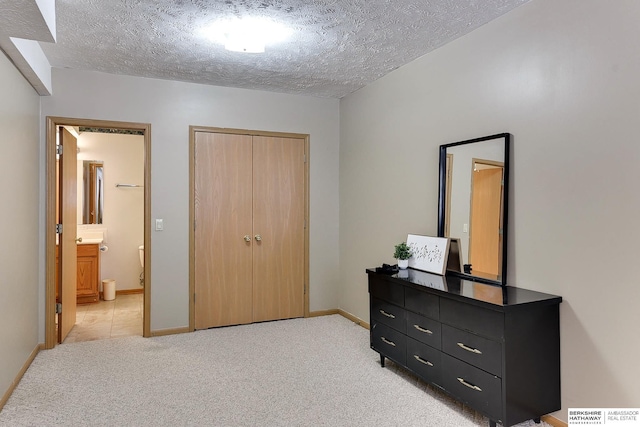 bedroom featuring light carpet, a textured ceiling, baseboards, and a closet