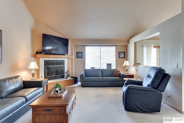 carpeted living area featuring a wealth of natural light, vaulted ceiling, a textured ceiling, and a tiled fireplace