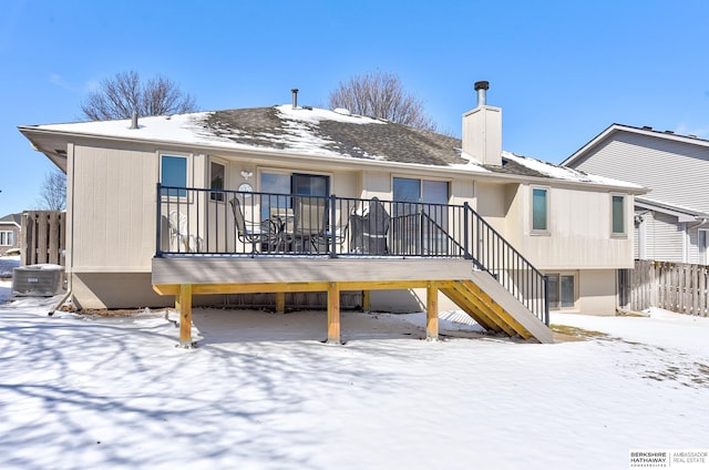 snow covered property with a chimney, stairway, and central AC