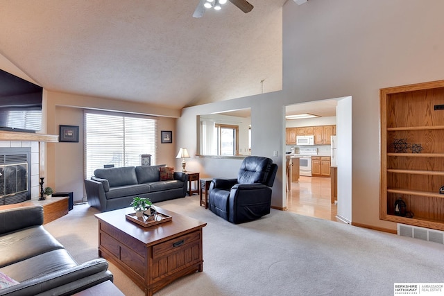 living room featuring a fireplace, light colored carpet, visible vents, a textured ceiling, and high vaulted ceiling