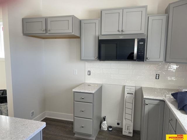 kitchen with tasteful backsplash, dark wood-type flooring, gray cabinets, and baseboards