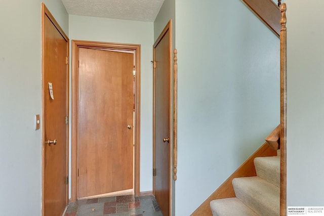 hall featuring stairs, baseboards, and a textured ceiling