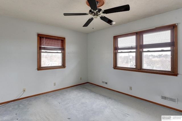 carpeted spare room with a ceiling fan, baseboards, and visible vents