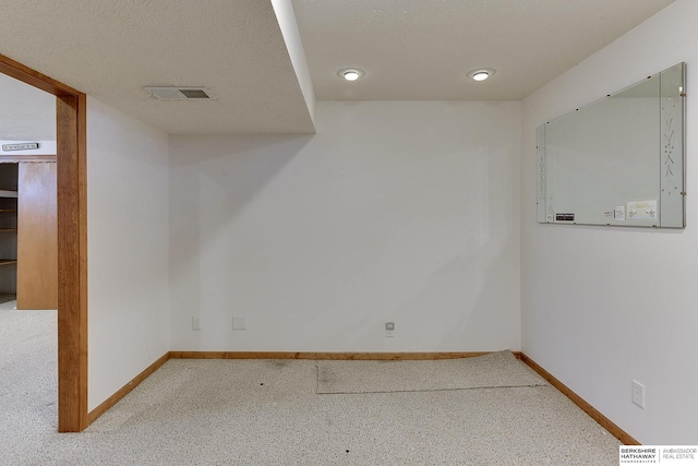 carpeted empty room featuring visible vents, baseboards, and a textured ceiling