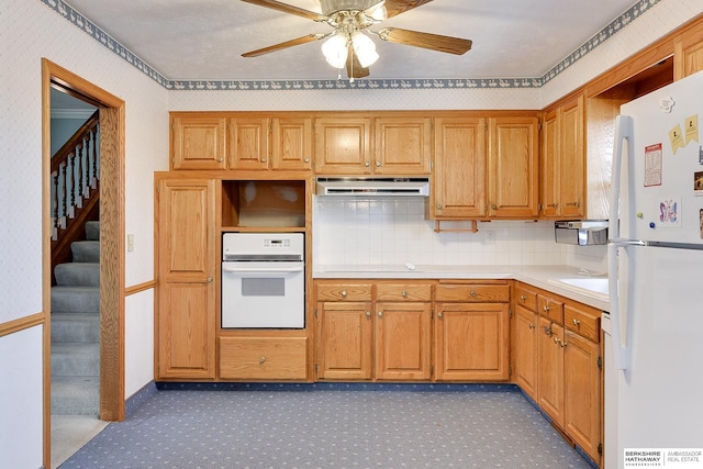 kitchen with ventilation hood, light countertops, decorative backsplash, white appliances, and a ceiling fan