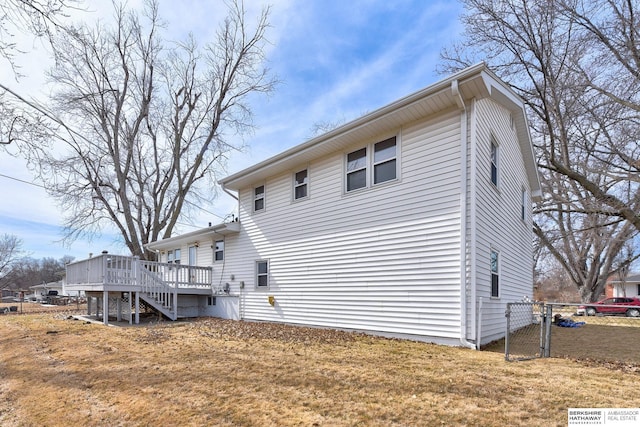 back of property featuring a lawn, a wooden deck, stairs, and fence