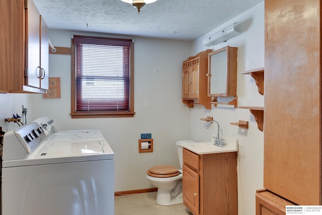 laundry area featuring washer and clothes dryer, laundry area, a textured ceiling, and baseboards