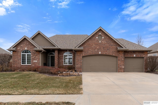 view of front of property featuring a garage, a front yard, and brick siding