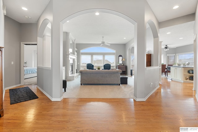 living area with a fireplace with raised hearth, plenty of natural light, and light wood-style floors