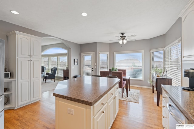 kitchen featuring arched walkways, light wood finished floors, a wealth of natural light, and dishwasher