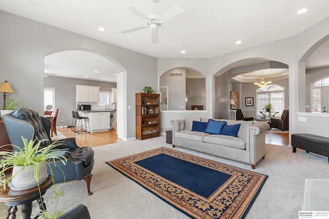 living area featuring ceiling fan with notable chandelier, baseboards, visible vents, and recessed lighting